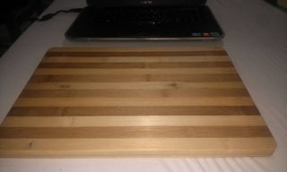 laptop behind wooden cutting board